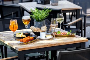 A wooden table with a variety of food and drinks, including bread, croquettes, and wine glasses.