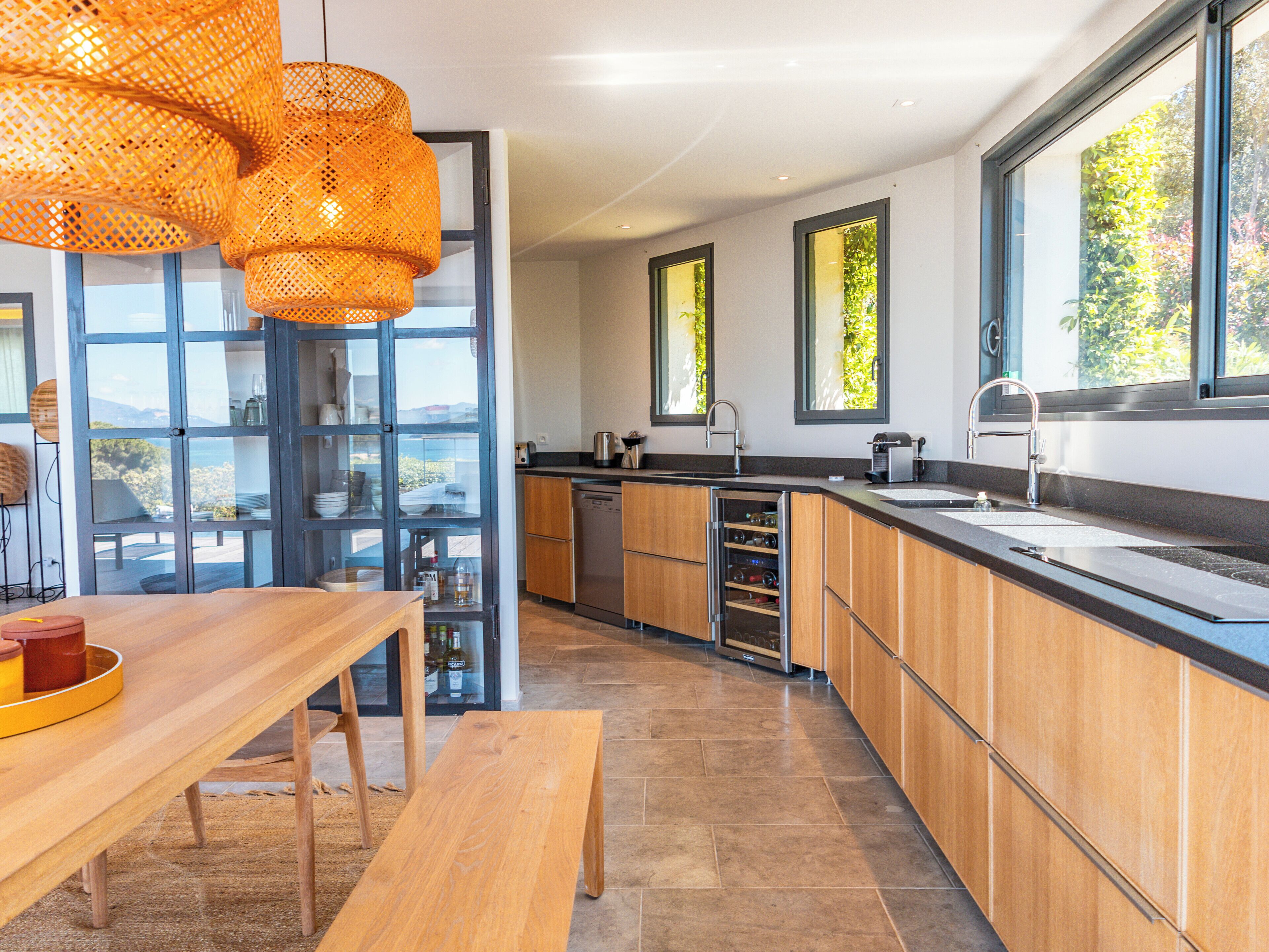 A modern kitchen with wooden cabinets, a built-in oven, and a large window overlooking a scenic view.