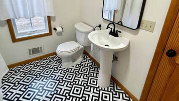 A bathroom with a toilet, sink, and mirror.