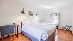 Une chambre avec deux lits, un bureau et une chaise.