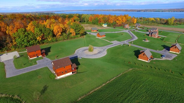 Luchtbeeld van een woongebied met meerdere huizen, een kronkelende weg en een meer op de achtergrond.