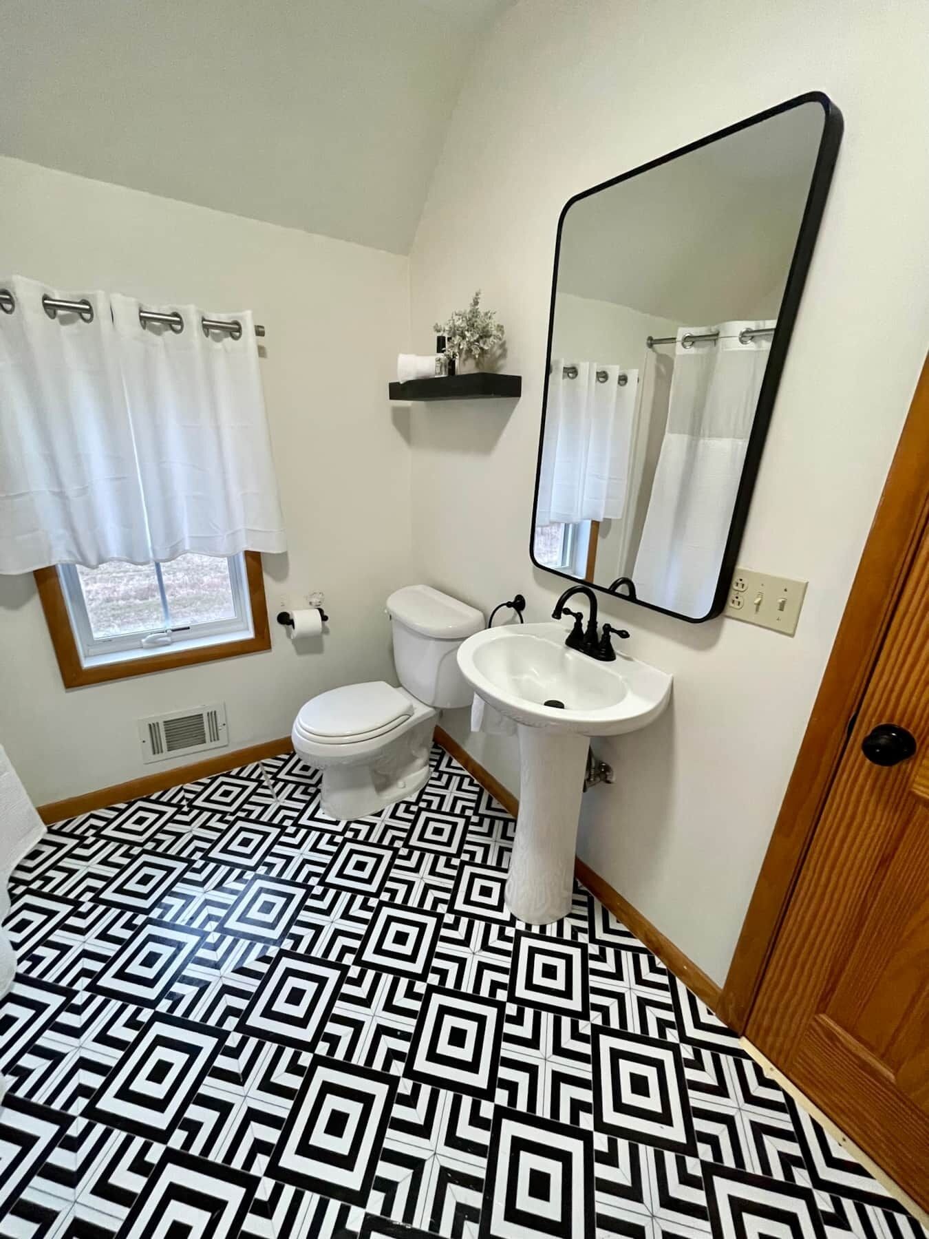 A bathroom with a toilet, sink, and mirror.