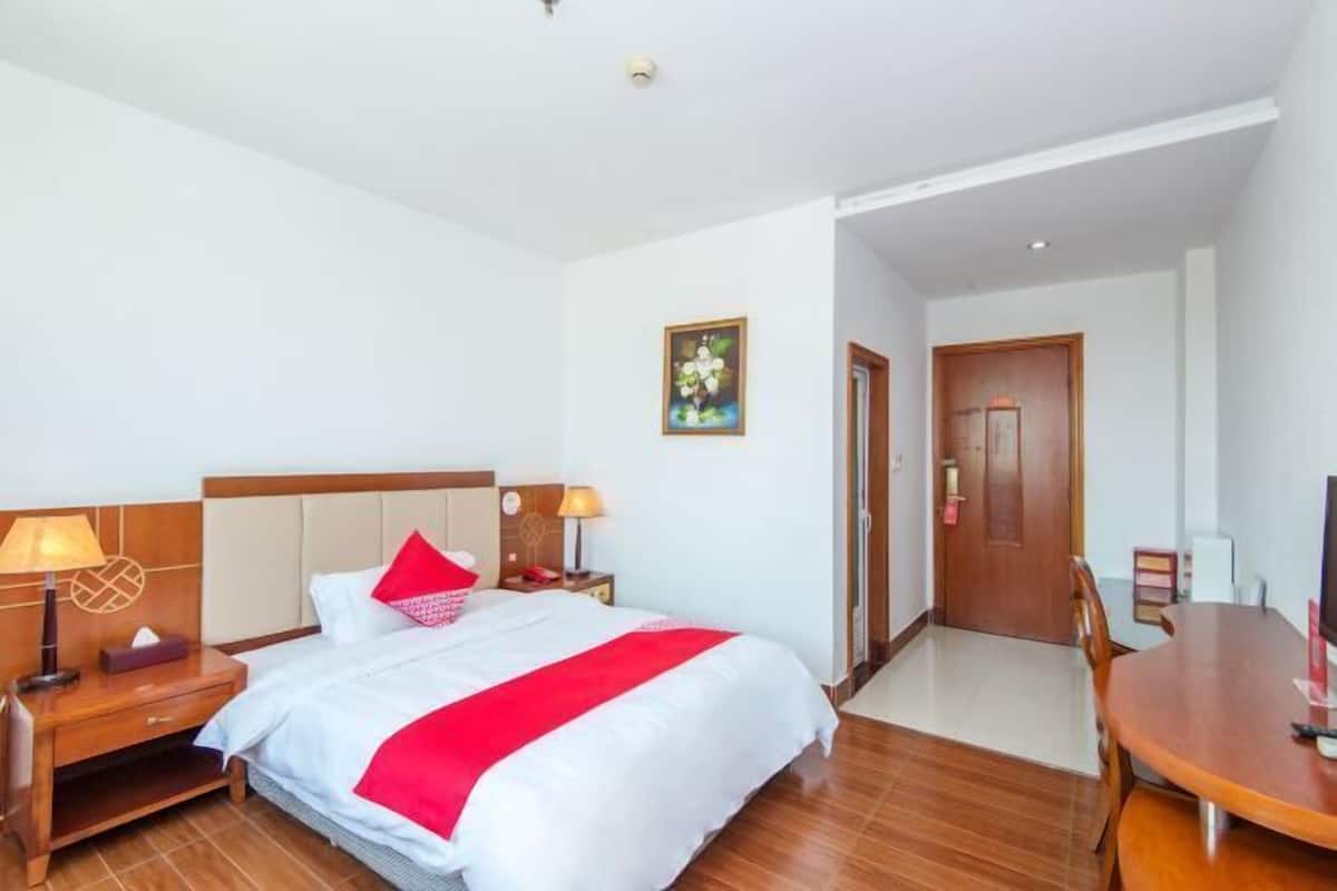 A hotel room with a bed, bedside tables, a desk, and a chair.