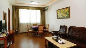 A hotel room with a wooden floor, a dining table with chairs, a sofa, a TV, and an air conditioning unit. - Jiating Hotel (Shenzhen)