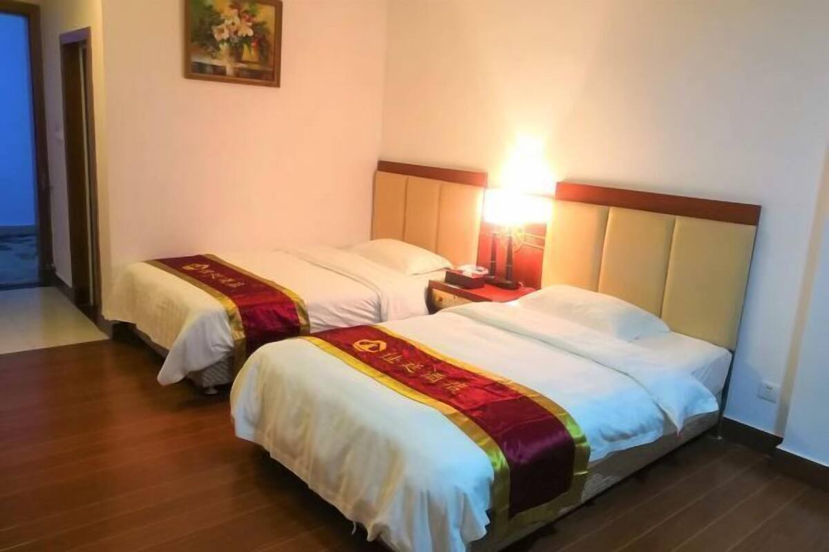 Two single beds with headboards, a nightstand, a lamp, and a painting on the wall.