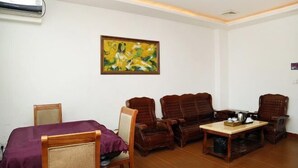 A room with a bed, two wooden chairs, a small table, and a painting on the wall. - Jiating Hotel (Shenzhen)
