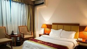 A hotel room with a bed, two chairs, a small table, a lamp, and an air conditioning unit. - Jiating Hotel (Shenzhen)