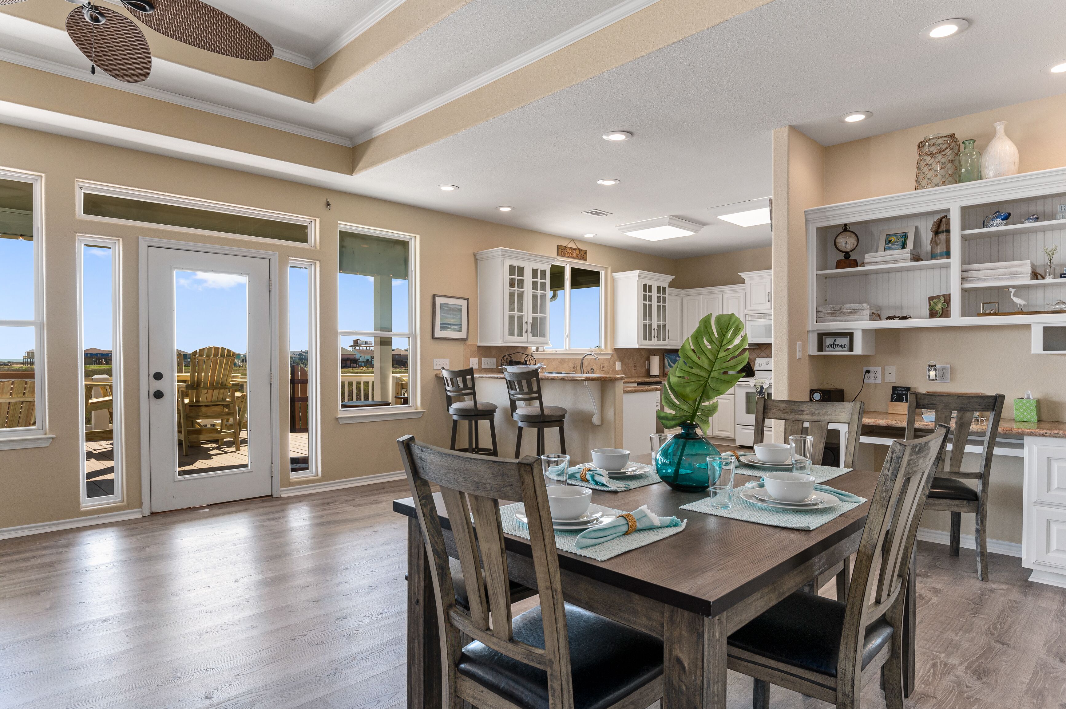 A spacious dining area with a wooden table set for four, surrounded by chairs.