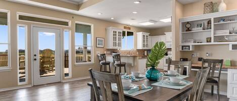 A spacious dining area with a wooden table set for four, surrounded by chairs.