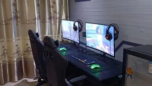 A gaming setup with two monitors, a keyboard, a mouse, and headphones. - Haiyuewan Holiday Hotel (Fangchenggang)