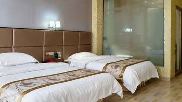 A hotel room with two beds, a large window, and a wall-mounted light fixture.