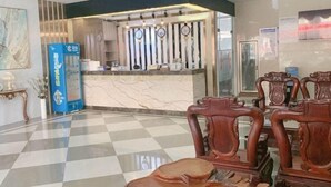 A hotel reception area with a checkered floor, a reception desk with a marble counter, and ornate wooden chairs. - Haiyuewan Holiday Hotel (Fangchenggang)