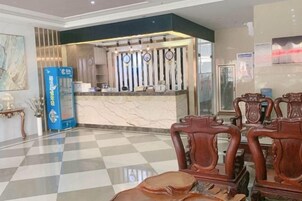 Un vestíbulo de hotel con mostrador de recepción, área de registro y zona de estar.