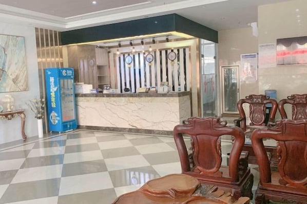 A hotel lobby with a reception desk, check-in counter, and seating area.