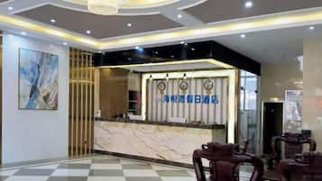 A hotel reception area with a marble counter, a chandelier, and a check-in desk.