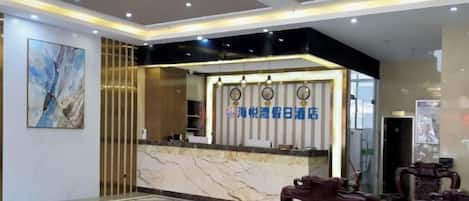 A hotel reception area with a marble counter, a chandelier, and a check-in desk.