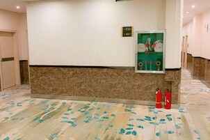 A reception area with a marble floor, a reception desk, and a fire extinguisher.