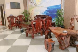 A checkered floor with a wooden dining table and chairs, a painting on the wall, and a potted plant. - Haiyuewan Holiday Hotel (Fangchenggang)