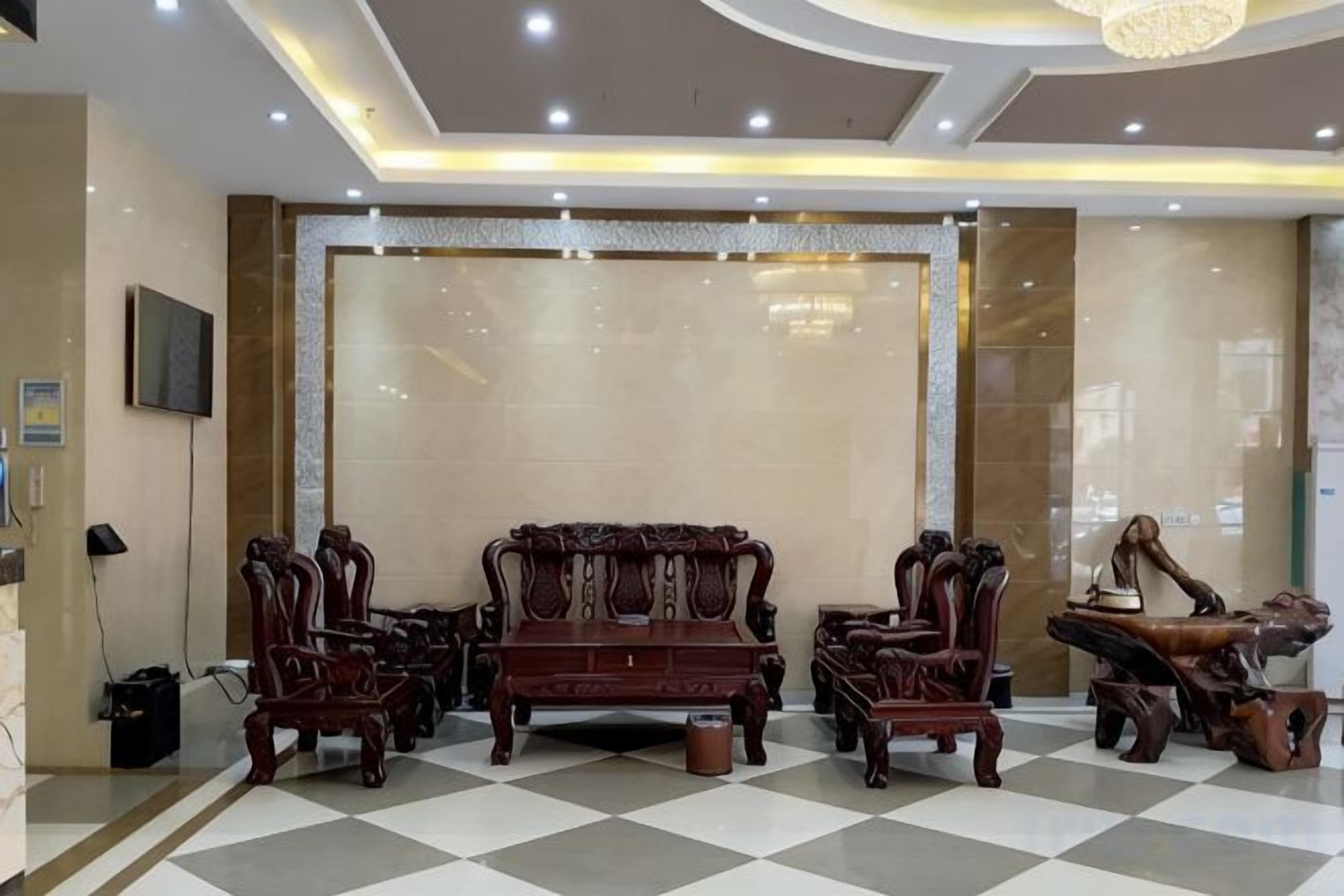 A lobby with a checkered floor, a large sofa set, and a wall-mounted television.