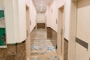Un pasillo con puertas a ambos lados, un suelo estampado y una pared de color claro.