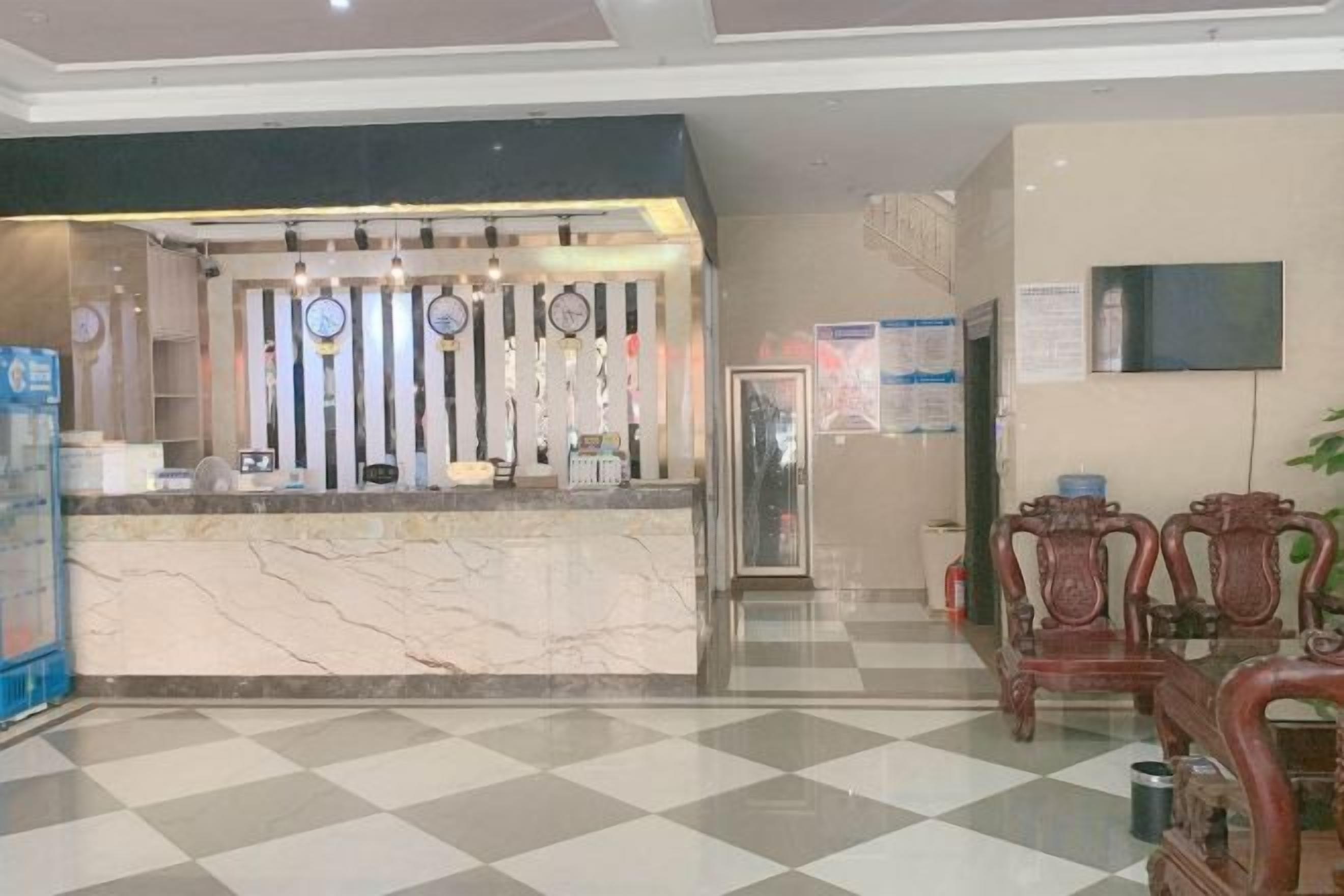 A hotel reception area with a marble counter, wooden chairs, and a check-in desk.