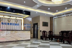 Zona de recepción de un hotel con mostrador de mármol, candelabro y suelo de cuadros.