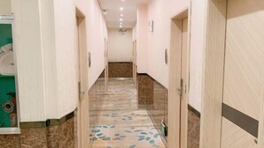 A hotel hallway with marble flooring, wooden doors, and a green wall with a window. - Haiyuewan Holiday Hotel (Fangchenggang)