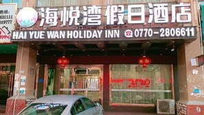 The exterior of Hai Yue Wan Holiday Inn with a large sign displaying the name and contact number. - Haiyuewan Holiday Hotel (Fangchenggang)