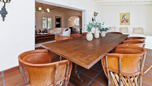 A spacious dining area with a large wooden table and leather chairs, a white interior, and a view into another room. - Historical 1937 Movie Colony Spanish Hacienda (Palm Springs)