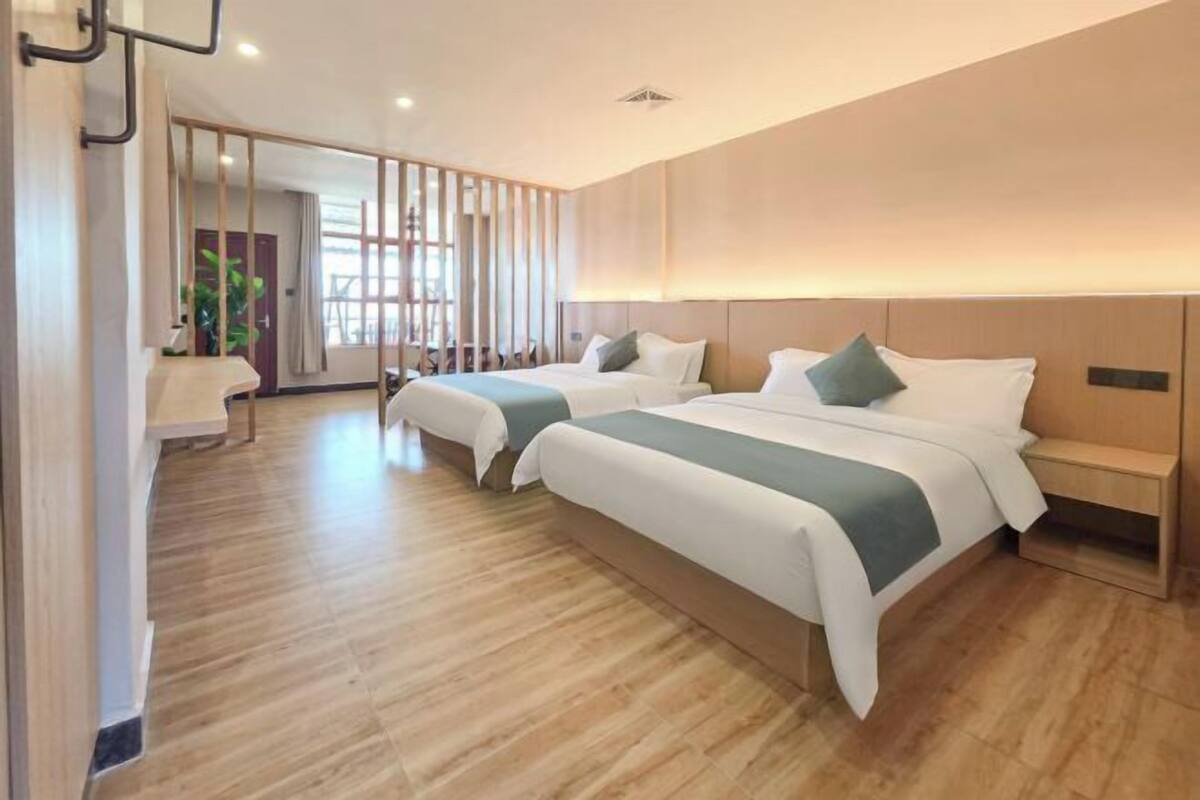 Een hotelkamer met twee bedden, een houten vloer en uitzicht op de omgeving.