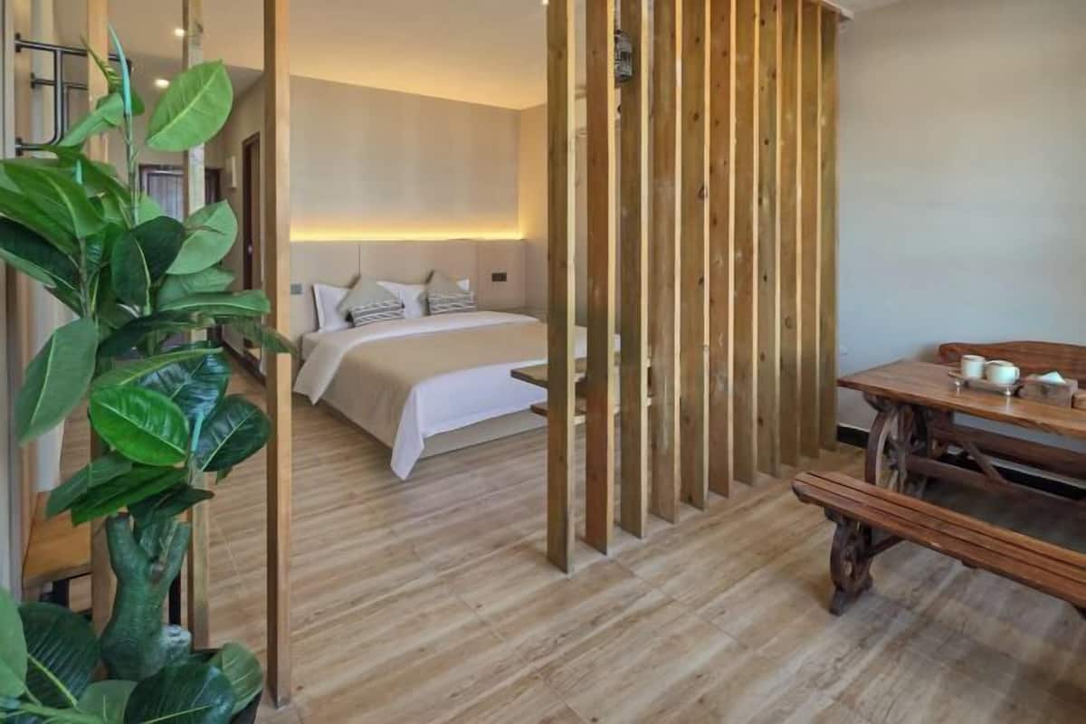 Een slaapkamer met een bed, nachtkastje en een houten scheidingswand.