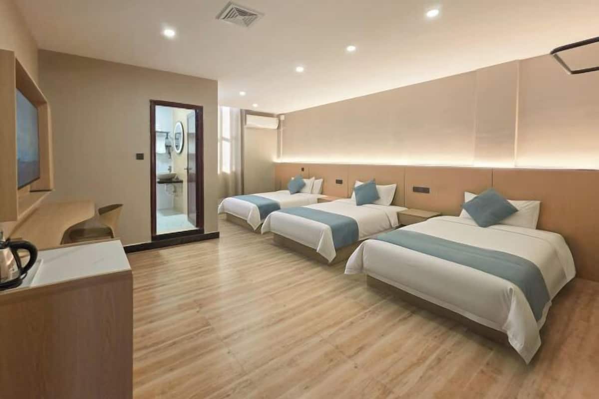 Een hotelkamer met drie bedden, een bureau en een televisie.