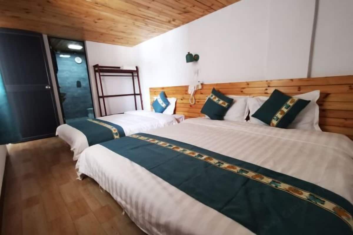 Een hotelkamer met twee bedden, een houten plafond, een telefoon aan de muur en een raam.