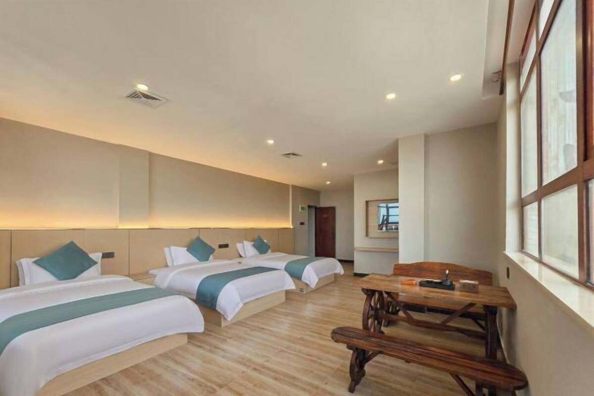 Een hotelkamer met twee bedden, een houten tafel en een groot raam.