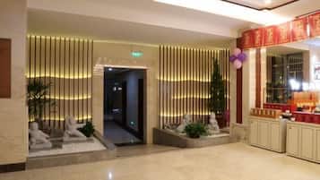 A lobby with a reception desk, a plant, and a decorative wall with vertical lines.