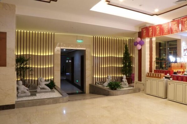 A lobby with a reception desk, a plant, and a decorative wall with vertical lines.