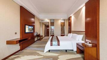 A hotel room with a bed, a TV, a desk, and a mirror.
