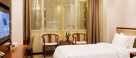 A hotel room with two beds, a TV, a desk with a chair, and a window with curtains.
