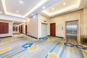A hotel corridor with a carpeted floor, doors, and an elevator. - Hongfeng Qiaolian Hotel (Yongchun)