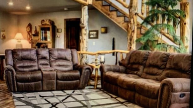 A living room with two brown leather sofas, a coffee table, and a staircase with wooden railings. - Cozy Cabin with Beautiful Views. Minutes from Downtown Custer (Custer)