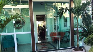 Varanda envidraçada com piso de madeira, plantas em vasos e área de refeições com mesa e cadeiras.