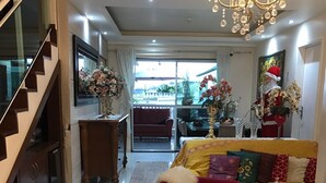 Uma sala de estar moderna com um sofá vermelho, um candelabro e uma escada.