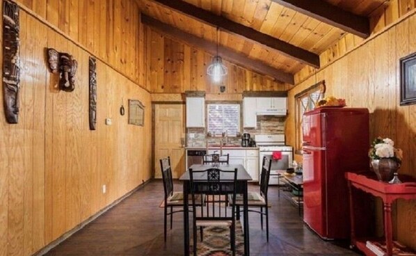 Un intérieur en bois comprenant un coin repas, une cuisine et un réfrigérateur rouge.