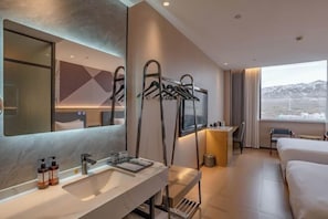 A hotel room with a large mirror, a sink, a towel rack, a bed, and a window with a mountain view. - Shangshi Hotel (Fuyun)