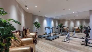 A gym with exercise equipment, seating areas, and potted plants.