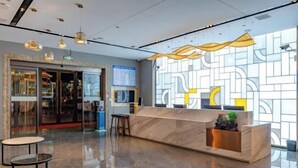 A modern reception area with a marble counter, a glass door entrance, and a decorative wall with geometric patterns. - Shangshi Hotel (Fuyun)