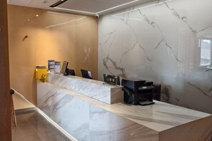 A reception desk with a marble counter, a computer, and a black chair. - Shangshi Hotel (Fuyun)