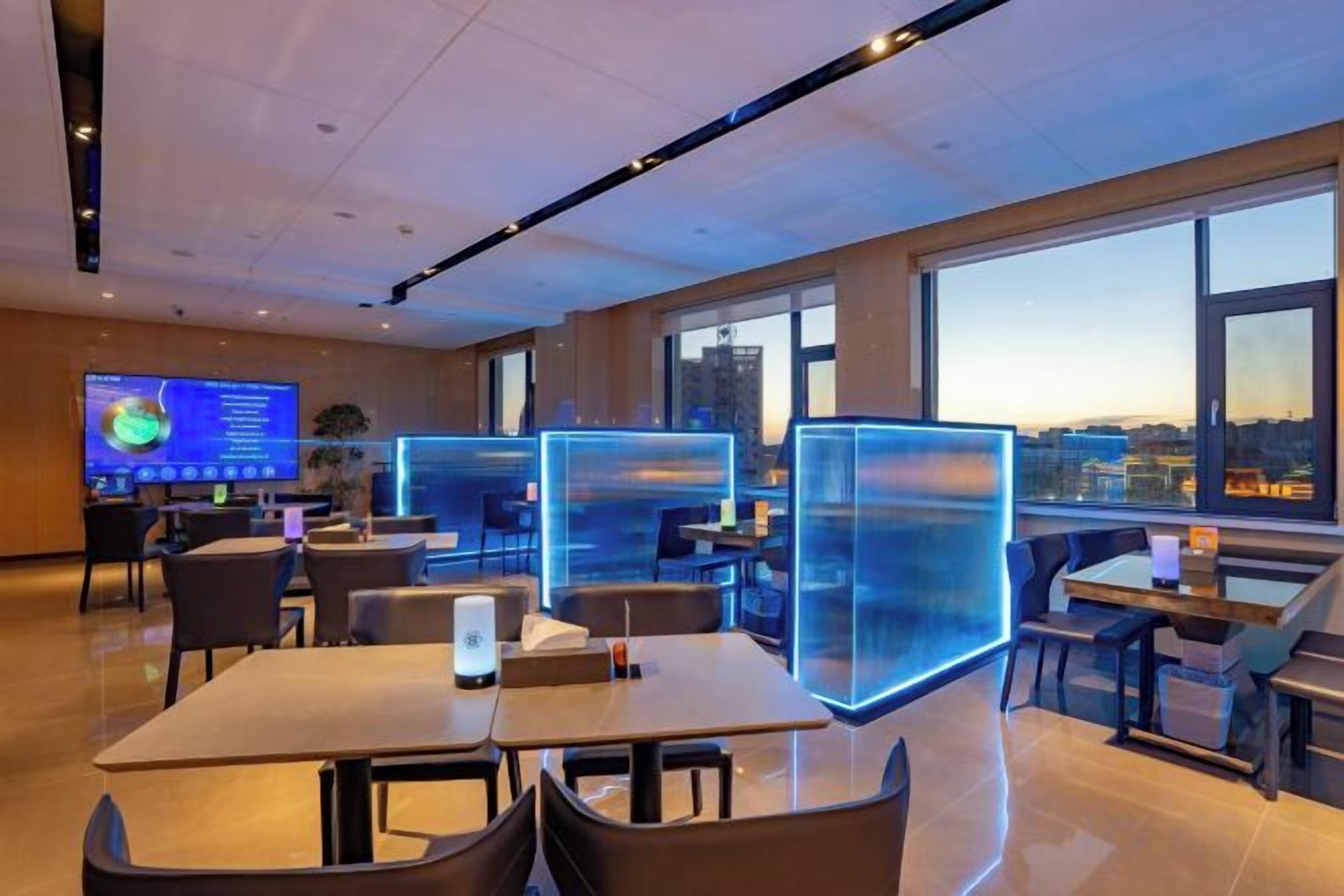 A modern hotel room with a large window, a flat-screen TV, and a desk with a chair.