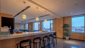 A modern kitchen with a central island, bar stools, and large windows offering a city view. - Shangshi Hotel (Fuyun)
