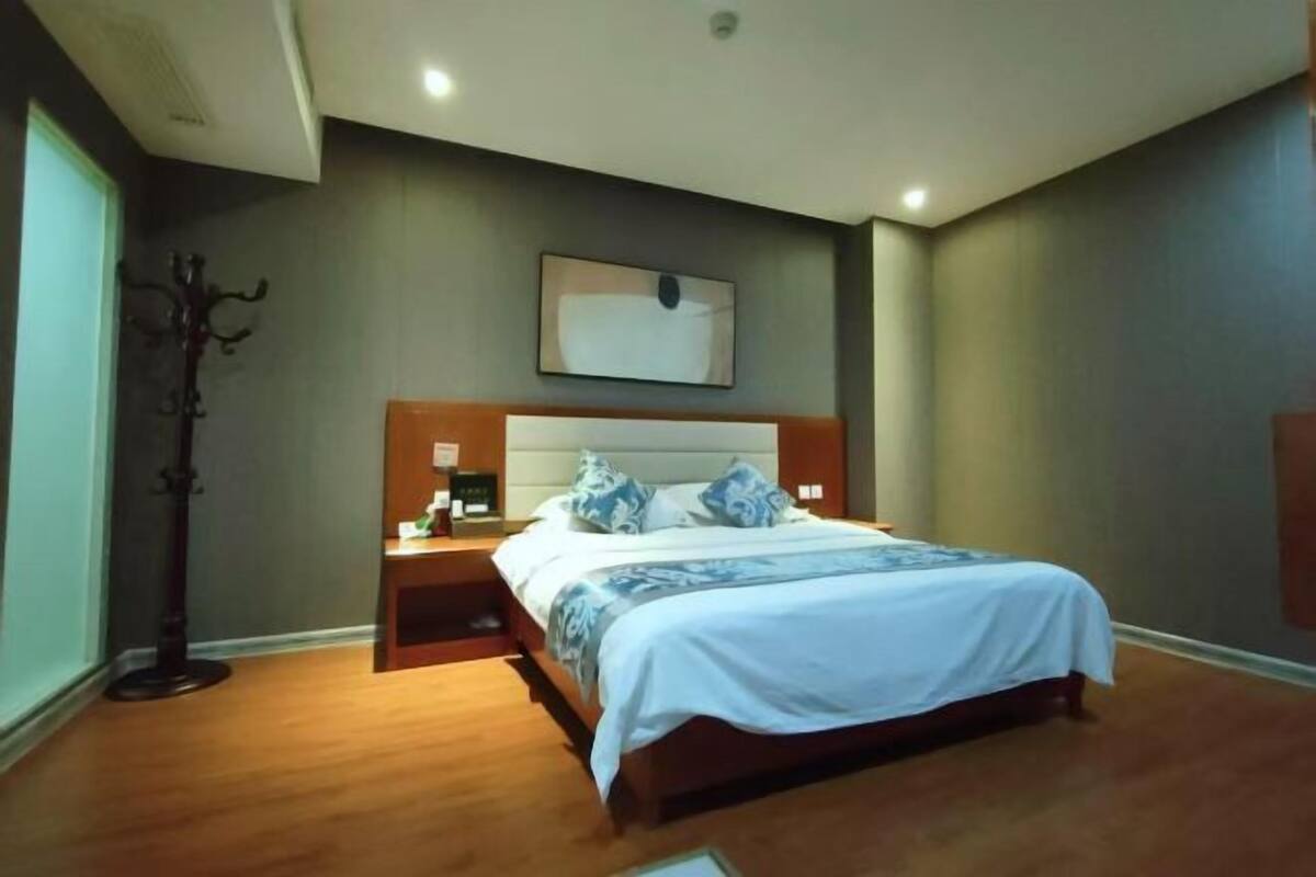 A bedroom with a bed, nightstand, and a coat rack.